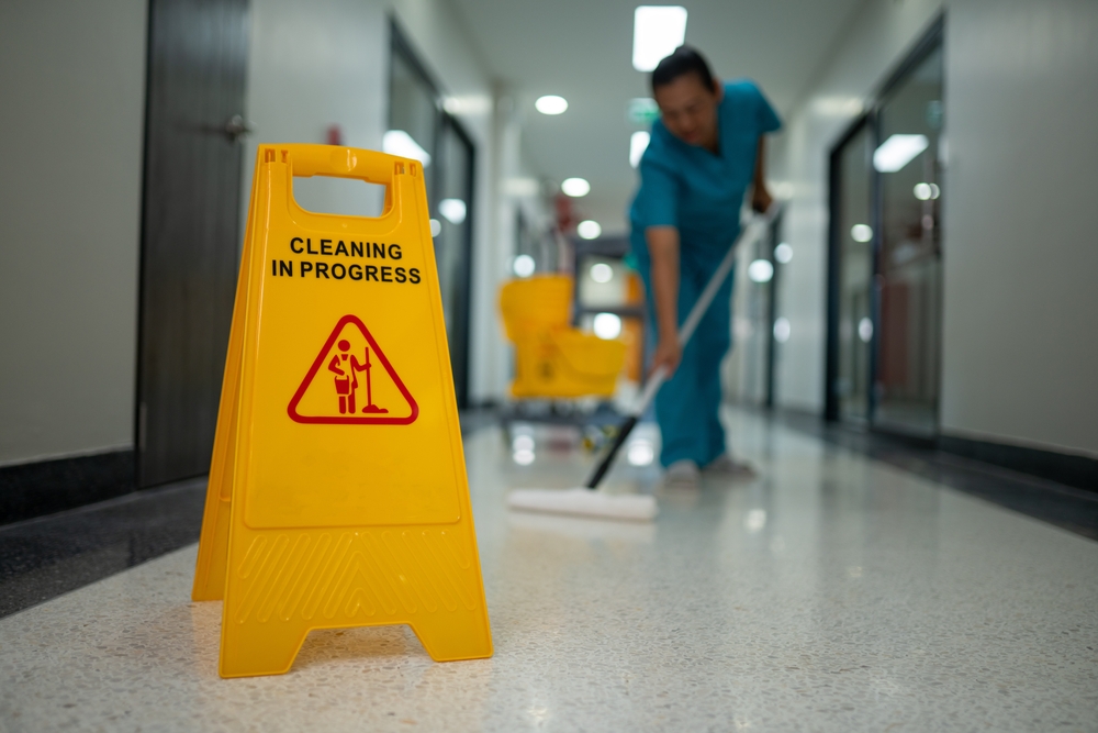 Uniformed day porter cleaning a commercial office lobby during business hours